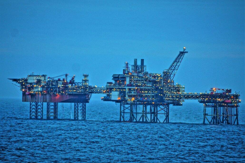 an oil drilling rig on the ocean at sunset.