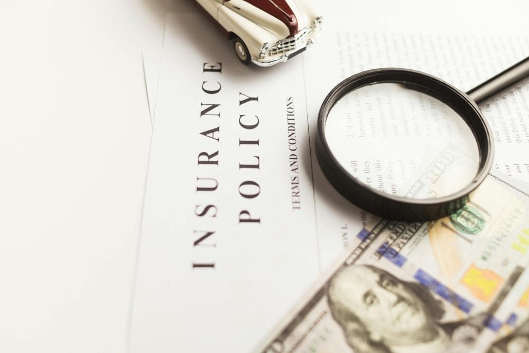 insurance policy with money and a magnifying glass