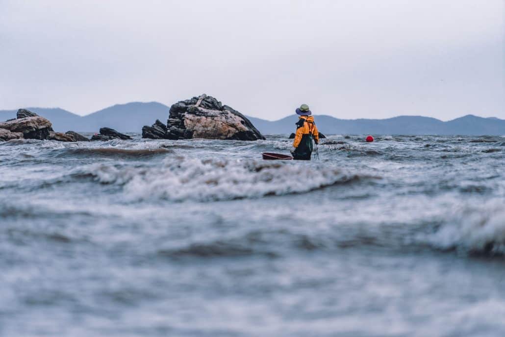 man standing in the ocean conducting observation.